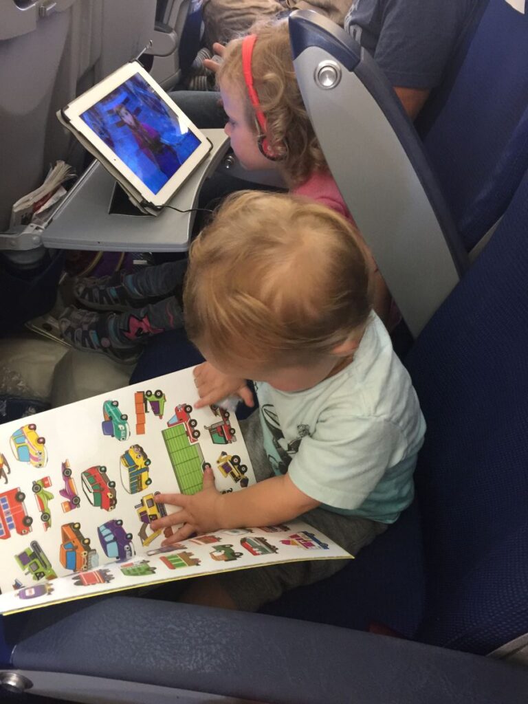 a 2-year old plays with a reusable sticker book on a long haul flight to Norway,