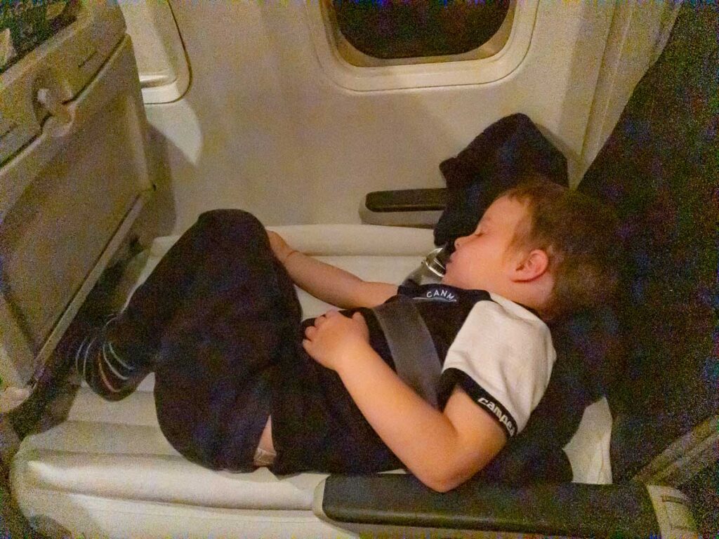 a toddler is fast asleep on a Flyaway Kids inflatable airplane bed.