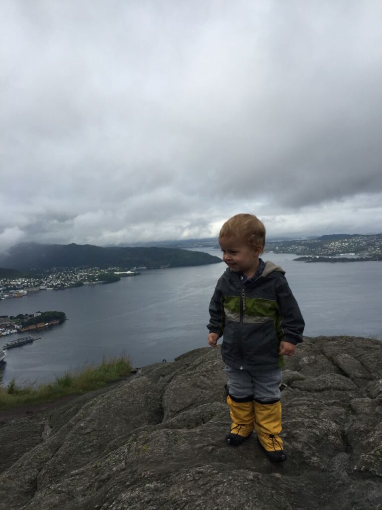 a 2-year old dresses warmly for a family hike in Norway in August.
