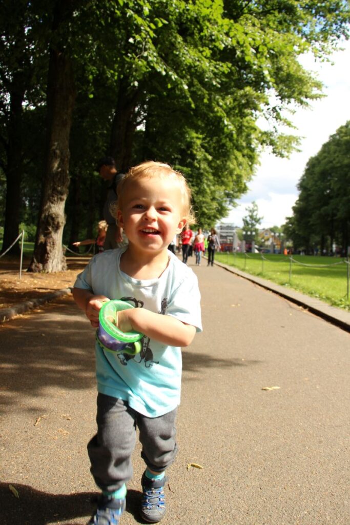 a toddler is all smiles as he enjoys a warm, sunny day in Oslo in July while on a family trip to Norway.