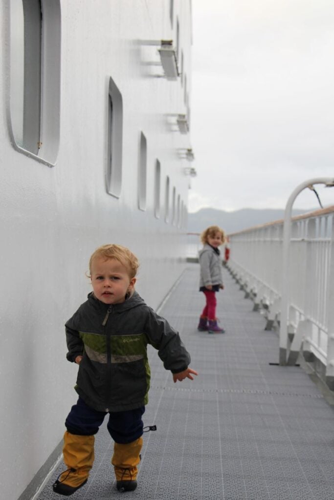Two small children are dressed warmly for a ferry ride on the Hurtigruten to Geiranger in August.
