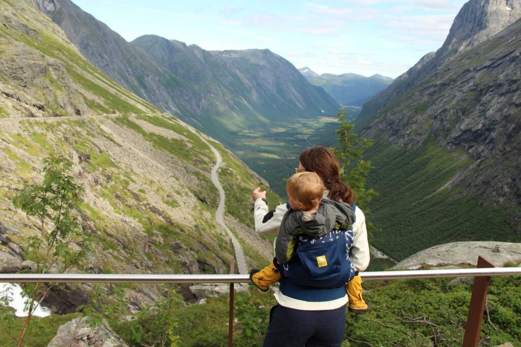 Celine Brewer carries her toddler in a Lillebaby toddler carrier while visiting Trollstigen on a trip to Norway with kids.