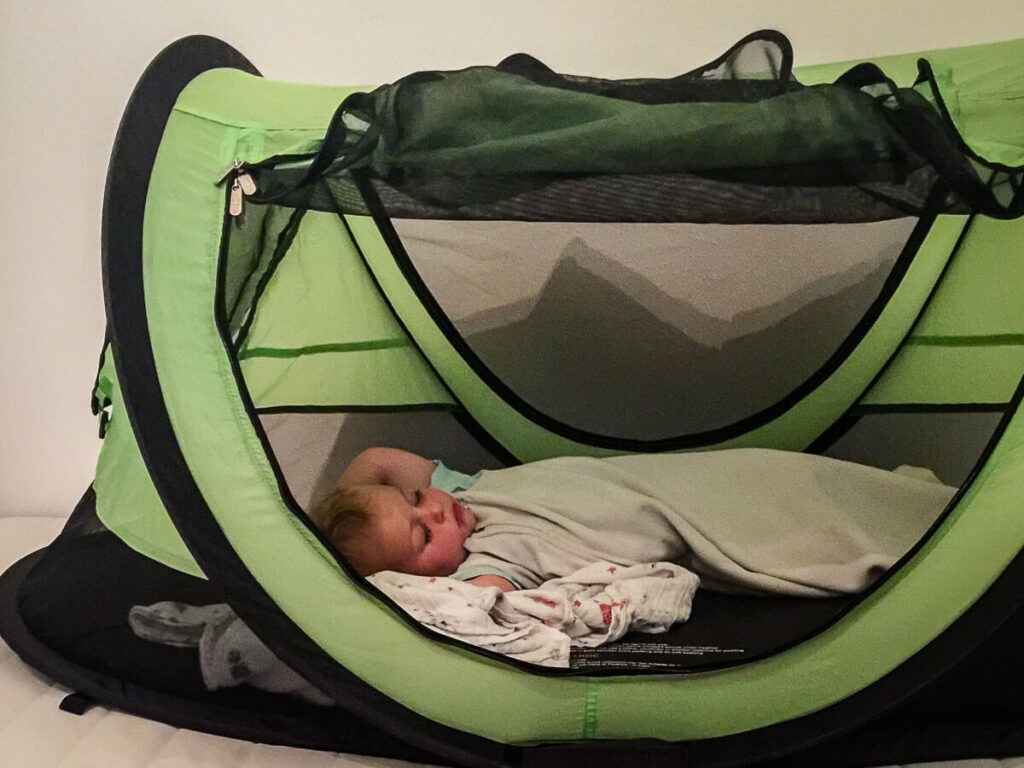 a toddler fast asleep in a PeaPod Plus travel tent.