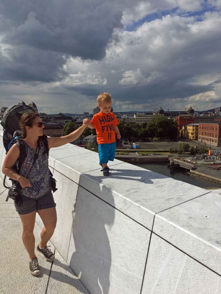 Celine Brewer, owner of the Family Can Travel blog, holds her toddler's hand while walking the roof at the Oslo Opera House.