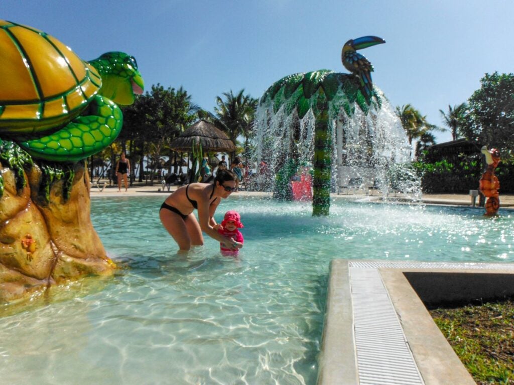 Celine Brewer, owner of the Family Can Travel blog, plays with her daughter in the splash pool at an all-inclusive resort in the Riviera Maya.