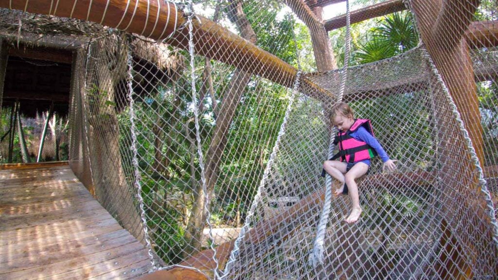 a 4-year old girl from the Family Can Travel blog, climbs down a rope slide at the Xcaret theme park.