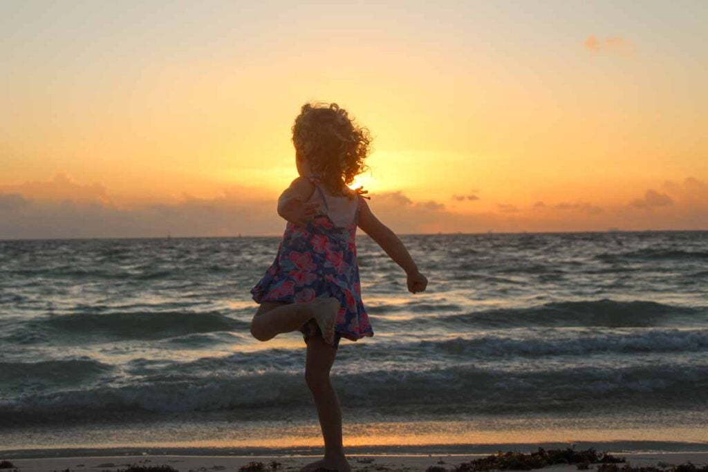 a 4-year old girl plays on a Playa del Carmen beach at sunrise.