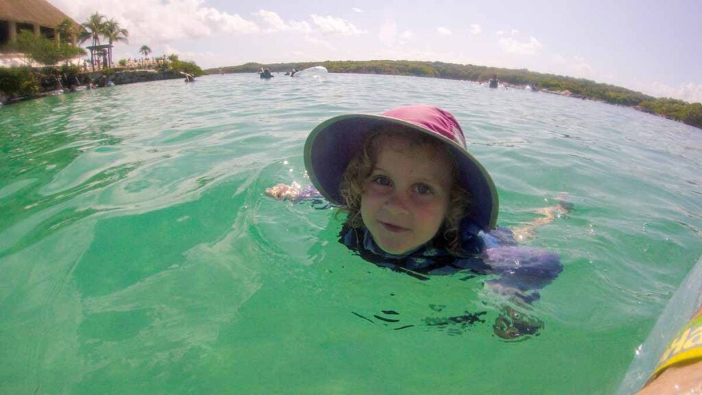 a 4-year old girl on a Riviera Maya family vacation swims in the lagoon at the Xel-Ha theme park.