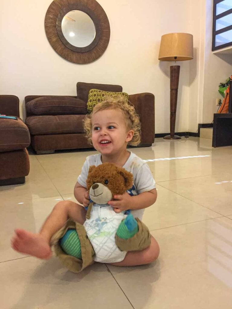 a toddler puts his stuffed bear in a diaper at his vacation rental in Playa del Carmen.