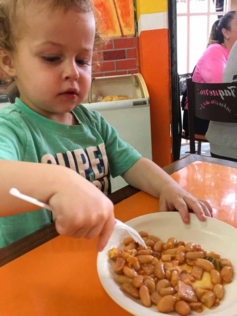 a 2-year old boy on a family vacation to the Riviera May eats beans at a kid-friendly restaurant in Playa del Carmen.