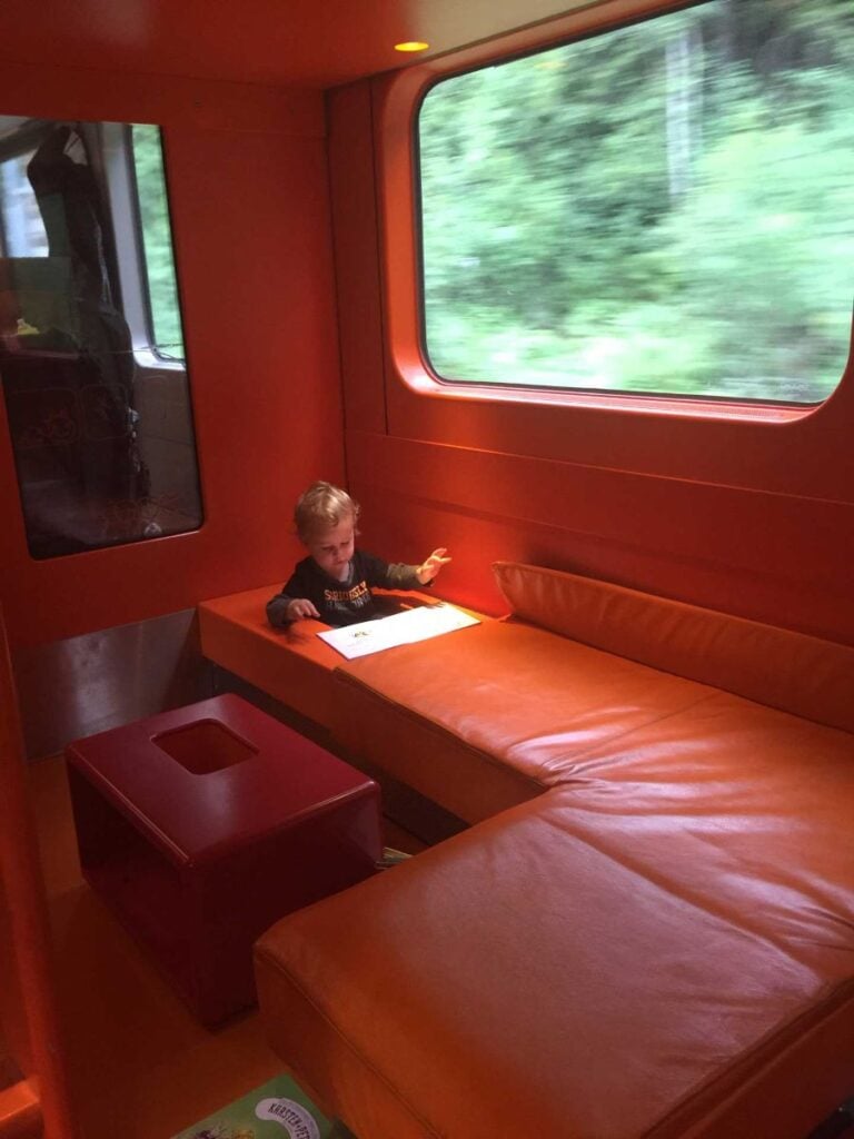 a 2-year old boy sits inside a little hole in the dedicated playroom in the family car on the Oslo to Bergen train.