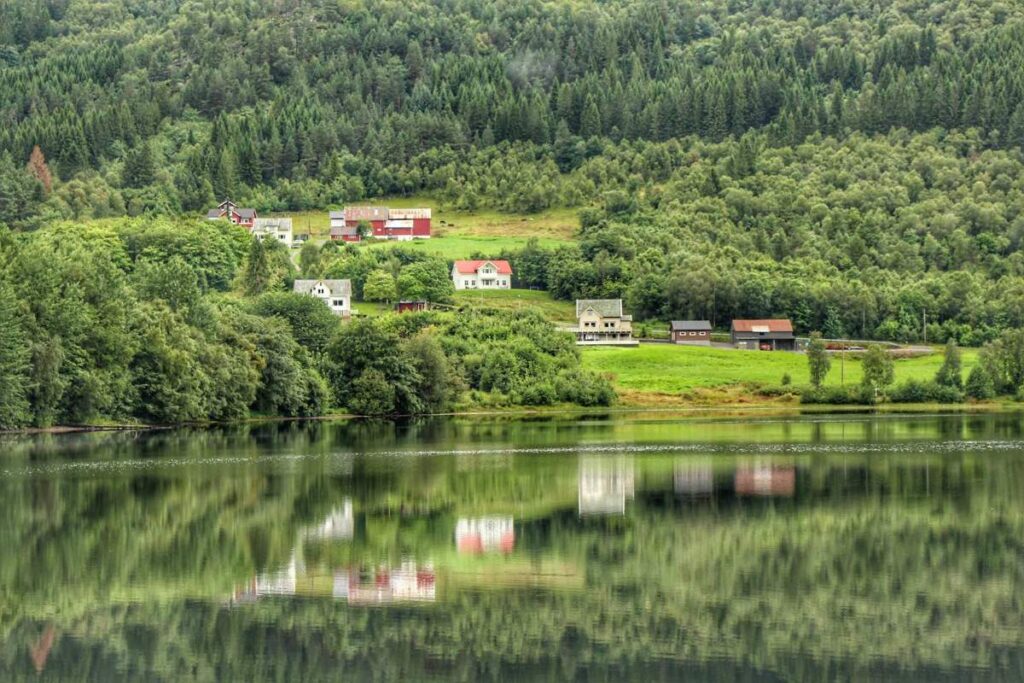 a charming village is reflected in the water of a lake on a Norway road trip with kids between Alesund and Molde.
