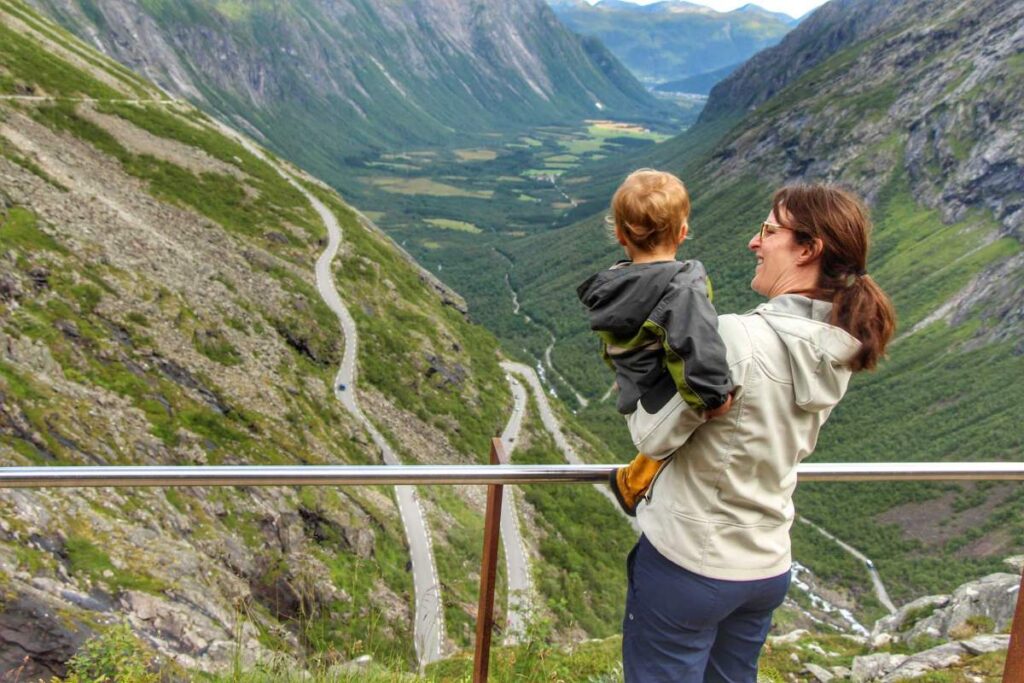 Celine Brewer, owner of FamilyCanTRavel.com, shows her 2-year old son the Trollstigen road while on a Norway road trip with kids.