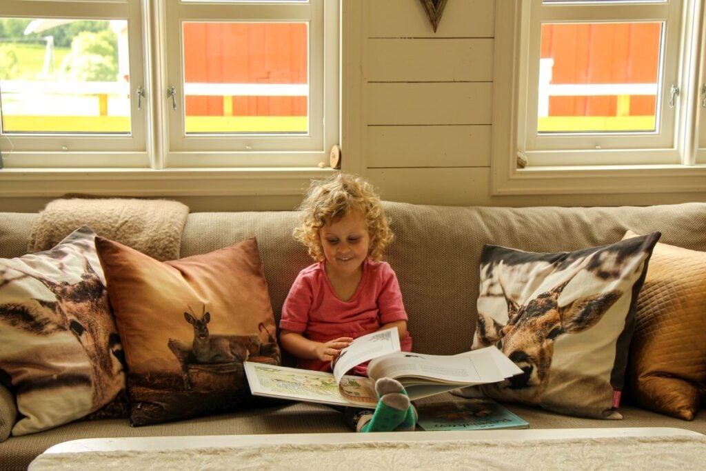 a 4-year old girl reads a book in an Airbnb while on a family road trip in Norway to the Atlantic Road.