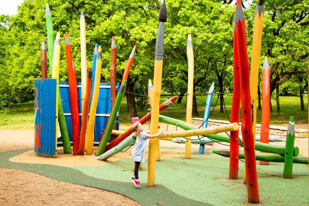 a 4-year old girl on a family trip to Budapest plays in a colorful pencil-themed playground on Gellert Hill.