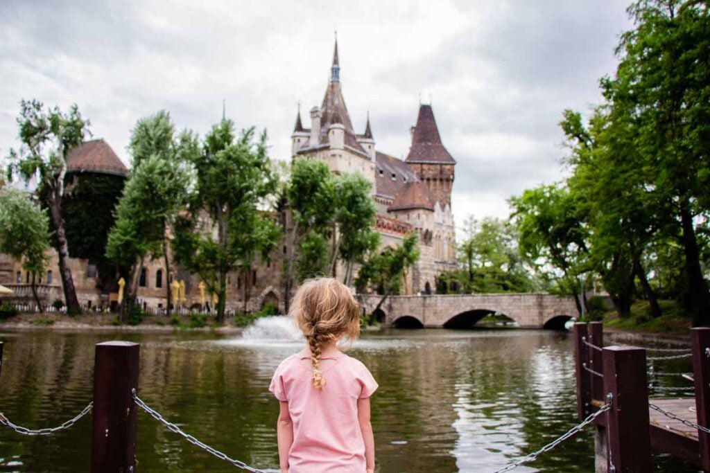 a 4-year old girl looks at Vajdahunyad Castle while on a family vacation to Budapest, Hungary.