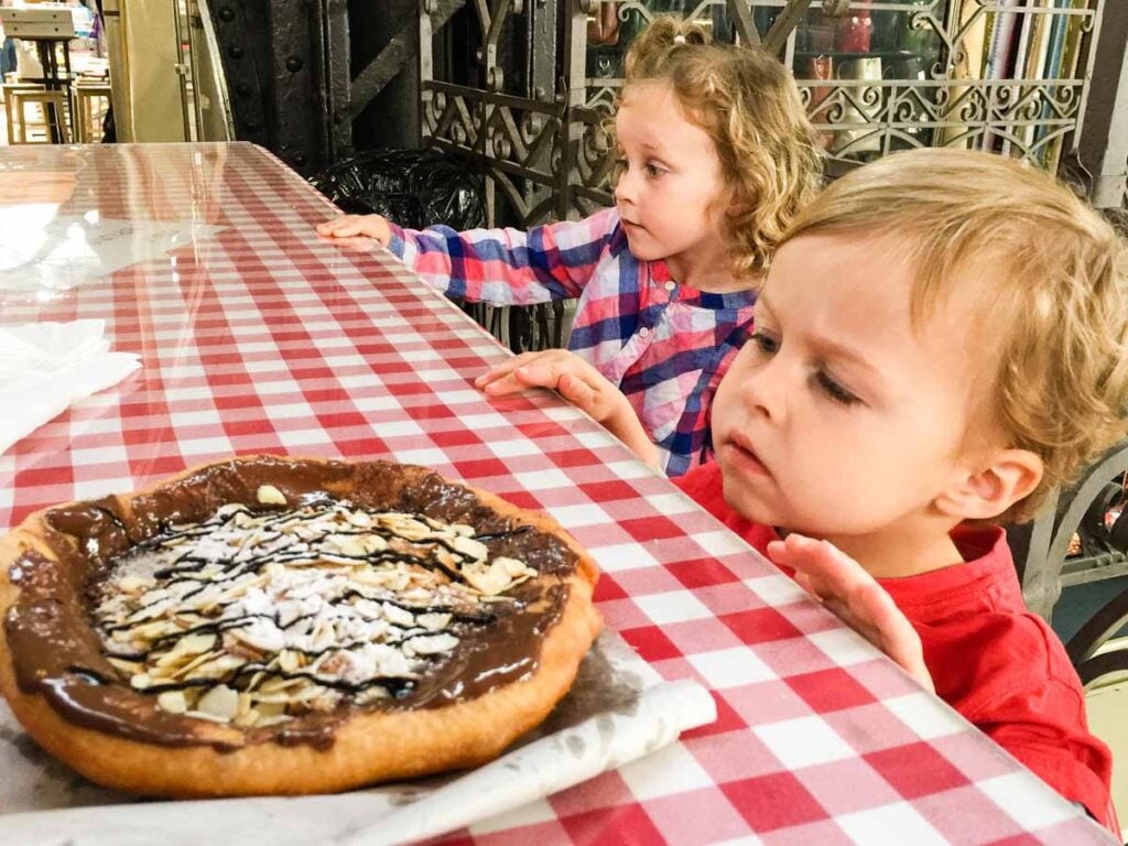 The Brewer kids, from the Family Can Travel blog, try lángos at the Great Market Hall in Budapest.