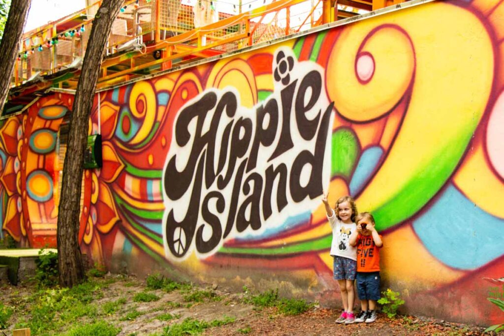 The Brewer kids, from FamilyCanTravel.com, stand in front of a very colourful Hippie Island sign on Margaret Island in Budapest.