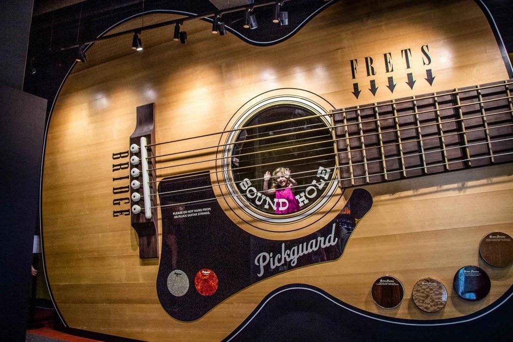 a 5-year old girl is all smiles looking out from inside a giant guitar at the Country Music Hall of Fame in Nashville, TN.