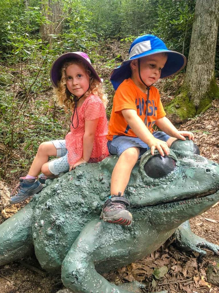 two kids play on a giant frog on the Great Woodland Adventure at Chimney Rock State Park.