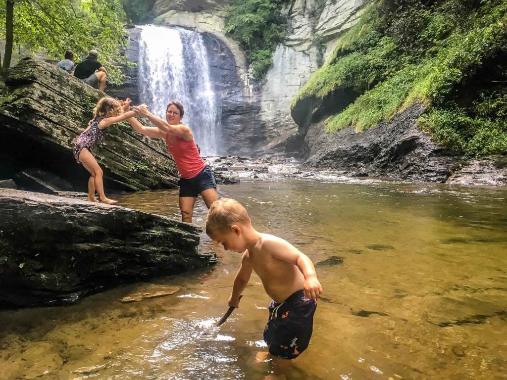 Celine Brewer, of the Family Can Travel blog, plays in the water with her kids at Looking Glass Falls in Pisgah National Forest.