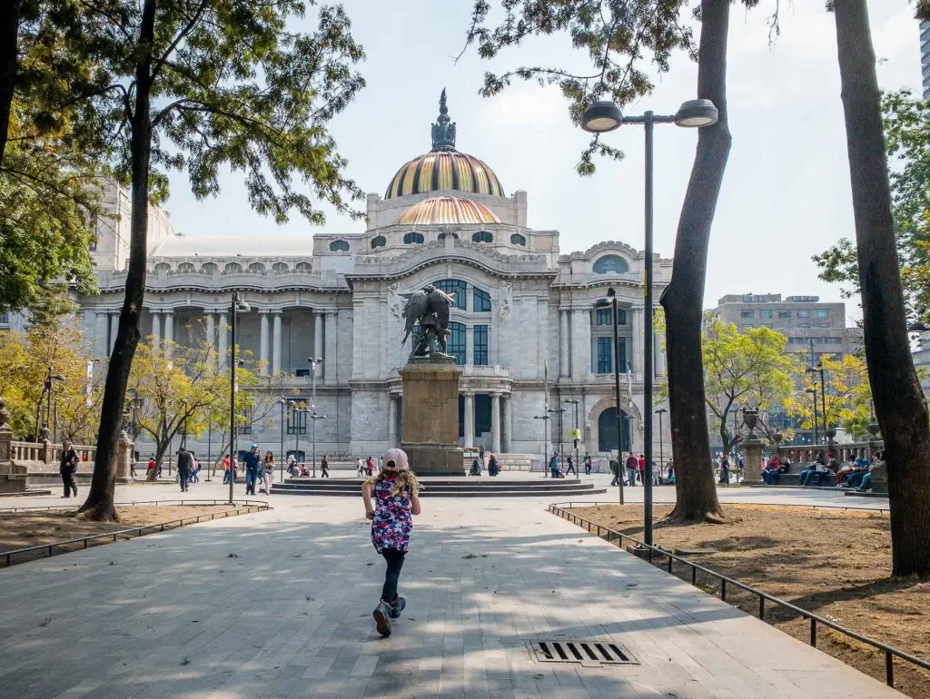 A girl runs towards Palacio de Bellas Artes in Alameda Central, Mexico City