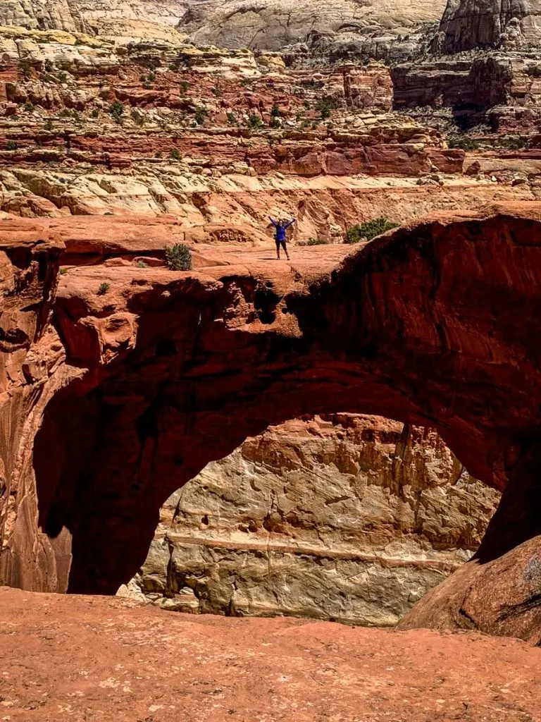 A hiker stands atop the Cassidy Arch in Capitol Reef National Park Utah