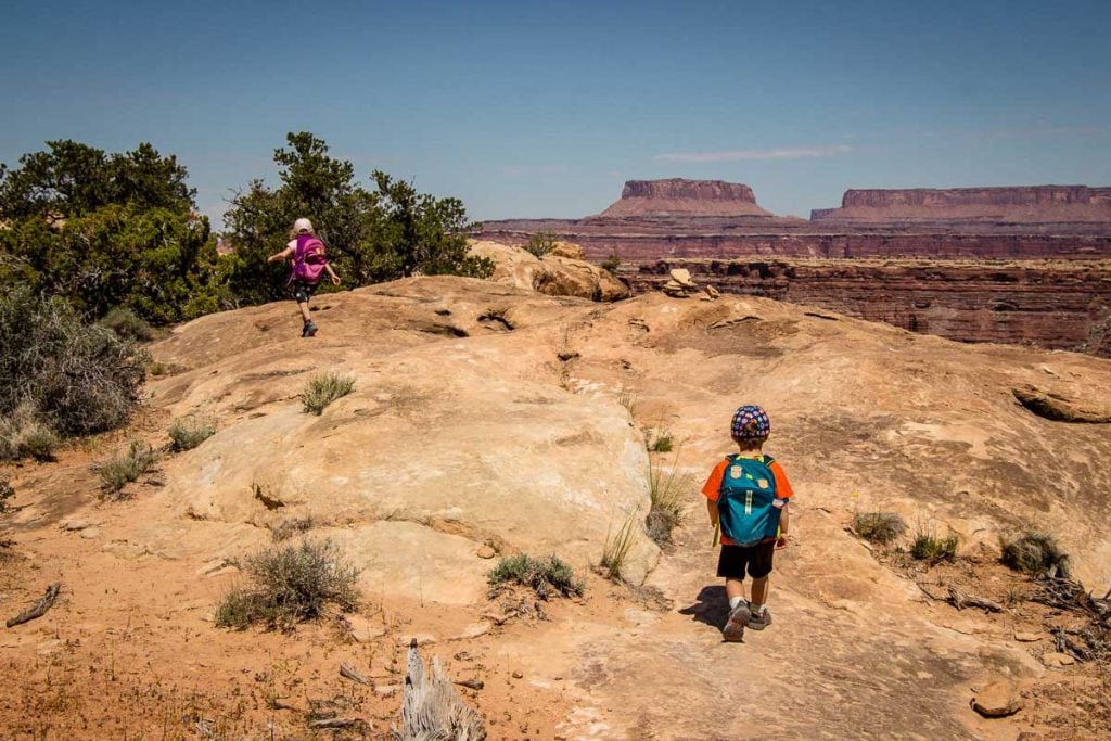 two small kids are hiking in canyonlands national park on a family trip to Utah.