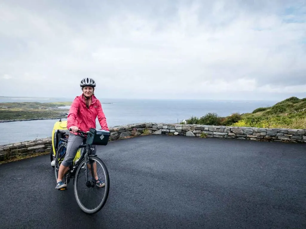 image of woman on bike pulling bike trailer in front of ocean