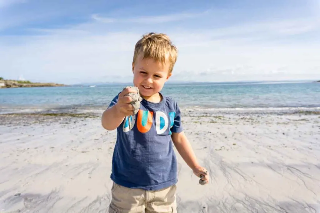 image of boy playing with sand on beach on Inishmore Aran Island Ireland