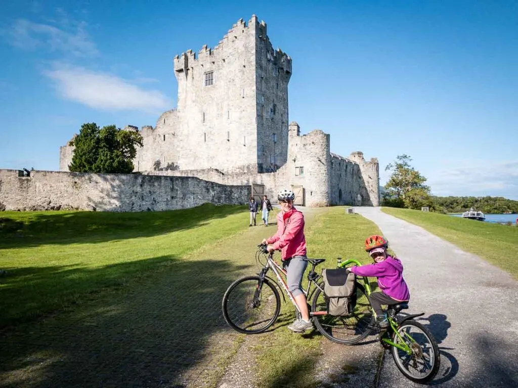 image of mother and child on bikes in front of Ross Castle in Killarney National Park