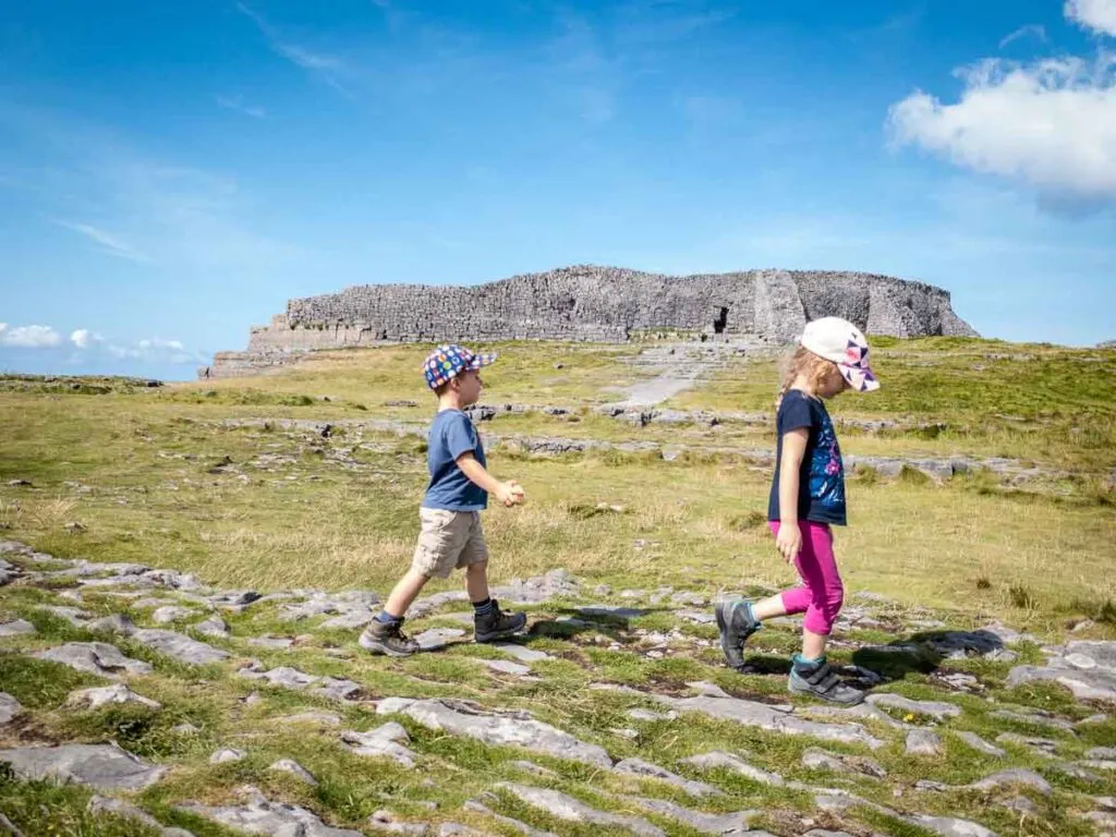 image of two kids walking in front of Dun Aonghasa, which is one of the best things to see on Inishmore with kids