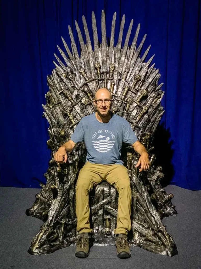 image of man sitting on replica of iron throne in Belfast Game of Thrones Exhibit