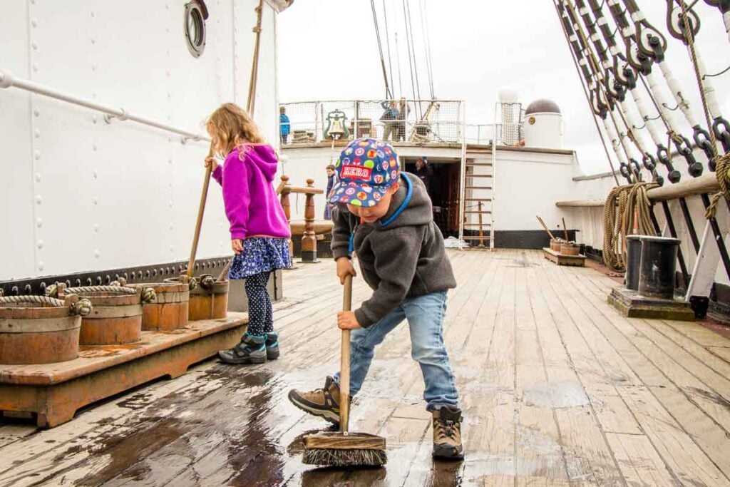 image of kids cleaning the floor of the Glenlee Tall Ship at Riverside Museum in Glasgow Scotland