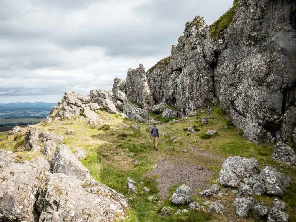 image of man walking along the huge rocks of the Whangie in Scotland