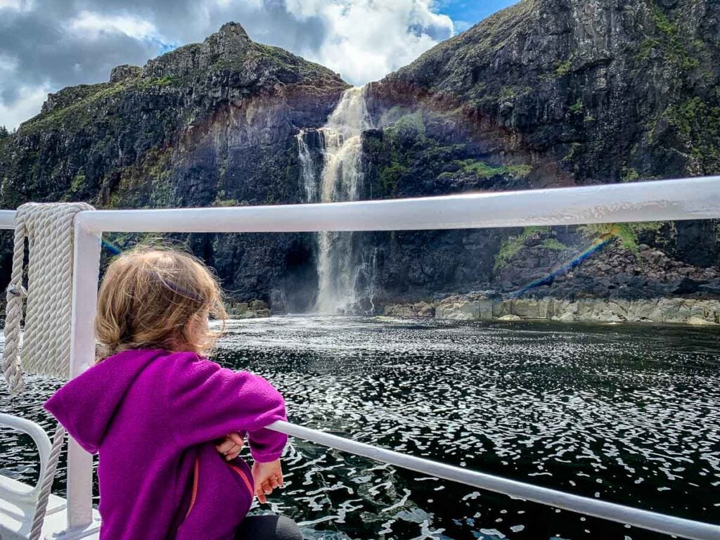 image of girl looking at waterfall from a boat on a boat cruise on Isle of Skye