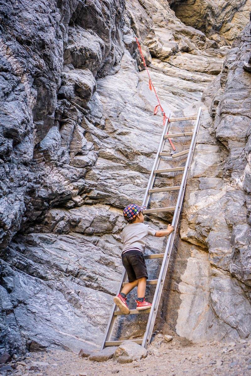 boy climbing down ladder on painted canyon trail in mecca wilderness near palm springs