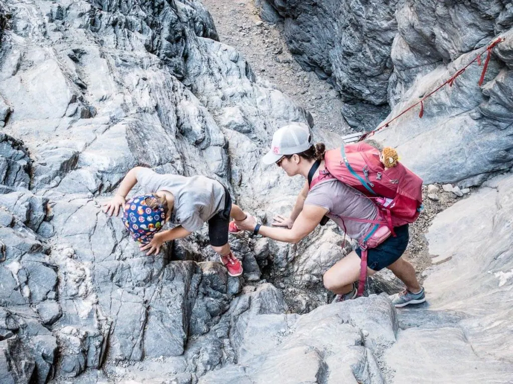 mother helping boy down to ladder in painted canyon in mecca wilderness