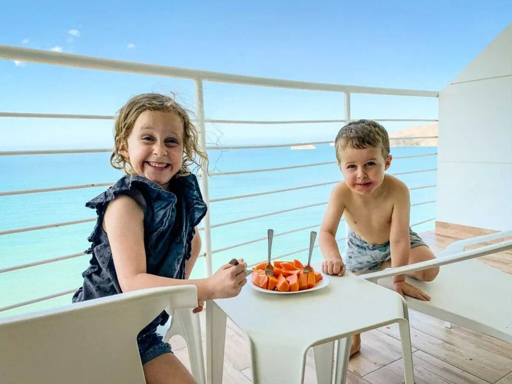 Two kids enjoying fresh papaya at an Airbnb overlooking the Caribbean in Colombia
