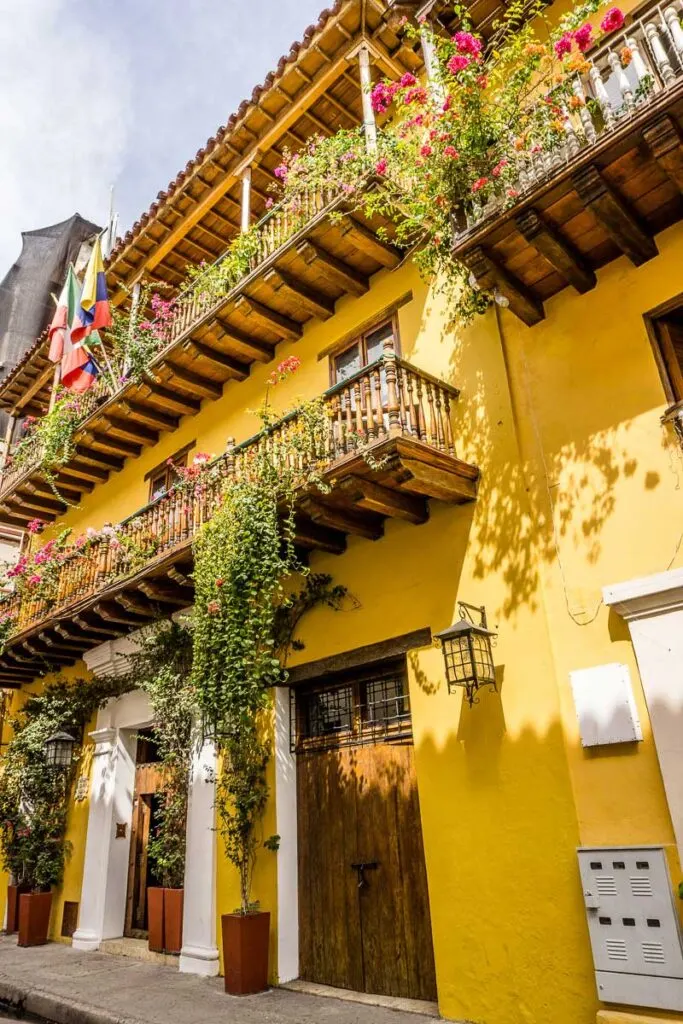 Bougainvillea flowers climbing walls and Colombian flags decorate colorful houses in Cartagena Old Town