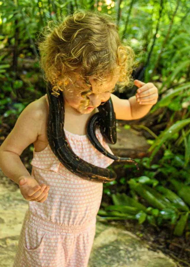A brave 4-year old girl holds a snake at the CroCo Cun zoo near Puerto Morelos