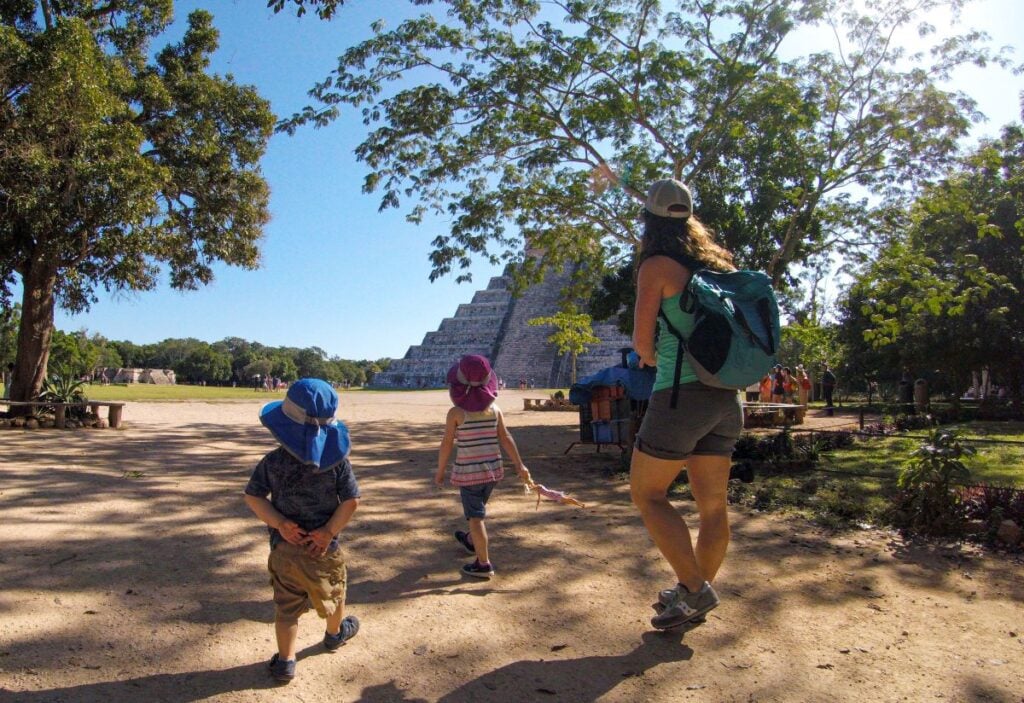 Celine Brewer, owner of FamilyCanTravel.com, walks through a shady spot while visiting Chichen Itza with her kids.