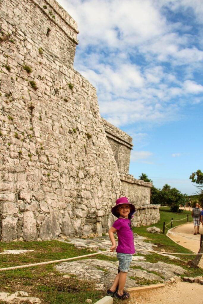 A Brewer child stands next to a structure while visiting the Tulum ruins with her family.