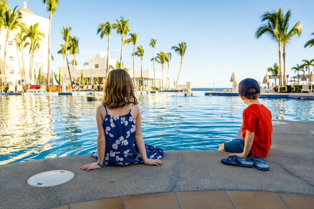 Kids sitting in front of pool at one of the best all inclusive family resorts in Mexico