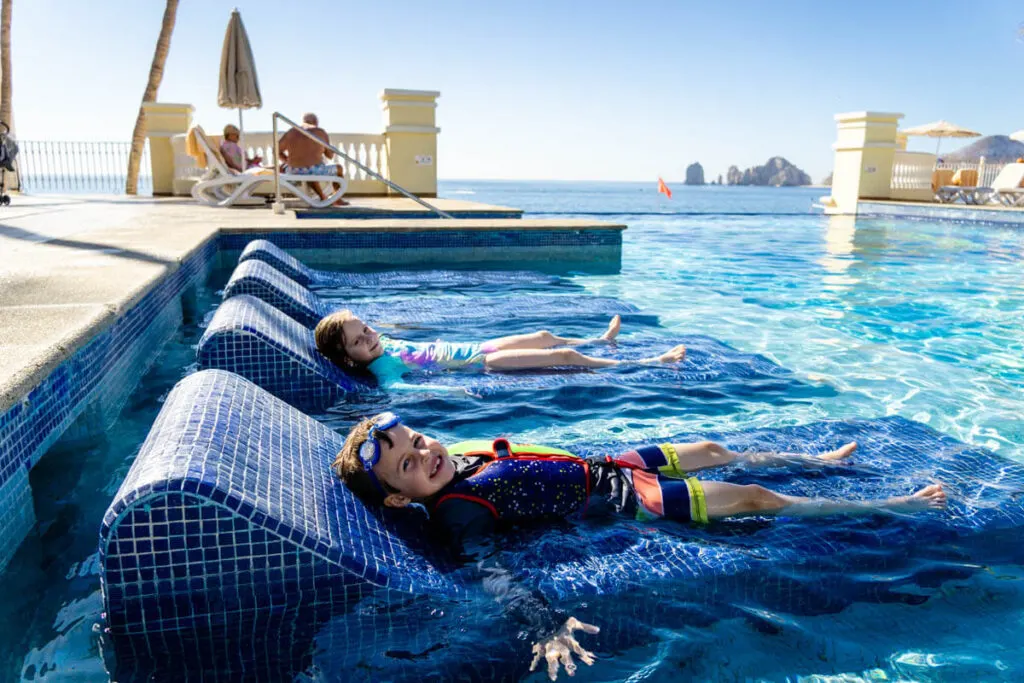Kids laying on lounge chairs wearing goggles (a must on beach packing list for family)