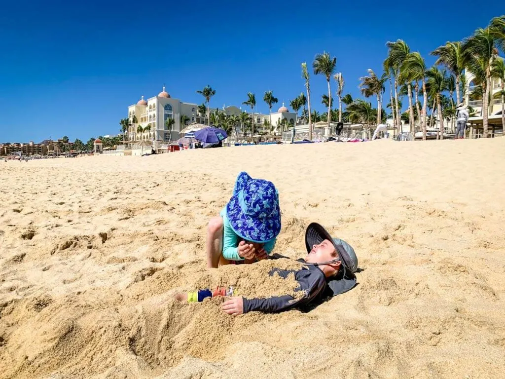 kids playing on beach wearing sun hats - packing lists for kids