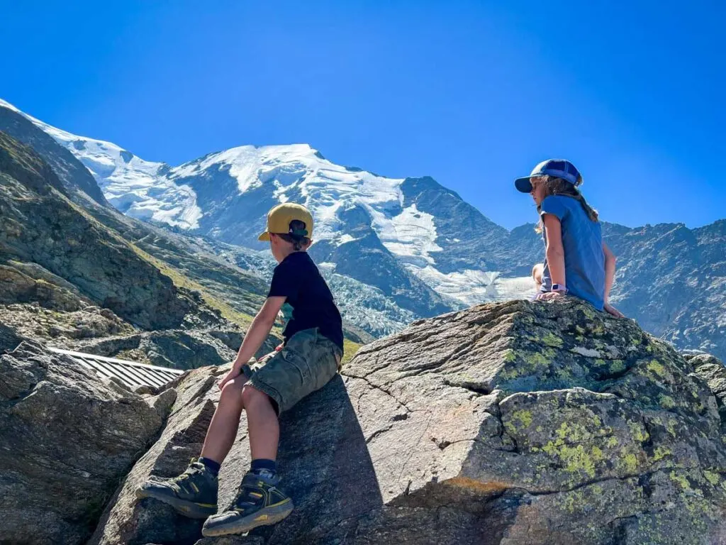 after a fun train ride on the Tramway du Mont Blanc, two kids enjoy views of the Bionnassay Glacier