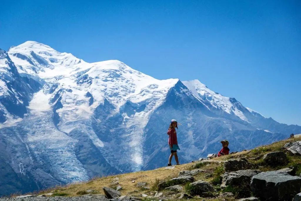 two kids play in an alpine meadow with Mont Blanc in the background