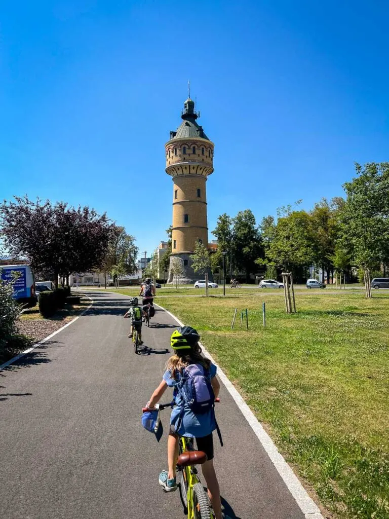 a family cycles past the Château d'eau in Selestat, France on their way to Ribeauville