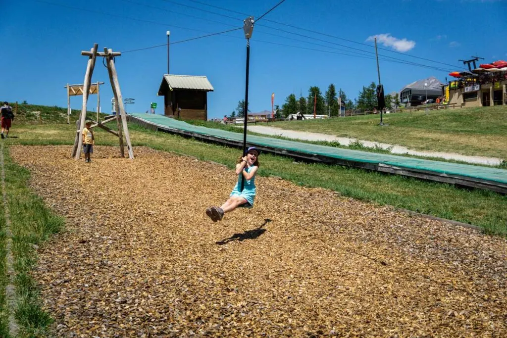a girl loves the zipline at the Camp des Marmottes playground at the mid-station in Serre Chevalier